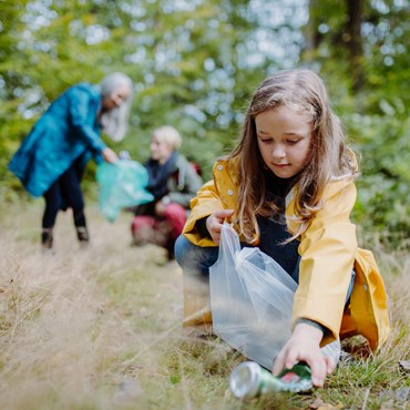 Pige og to voksne indsamler skrald i skoven (kilde: Colourbox)